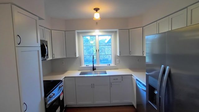 kitchen featuring white cabinets, appliances with stainless steel finishes, light countertops, and a sink