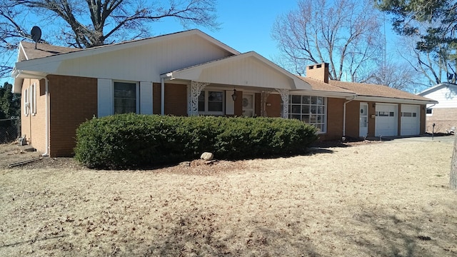 ranch-style home featuring brick siding, driveway, a chimney, and an attached garage