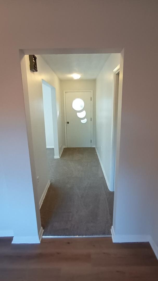 corridor with baseboards and wood finished floors