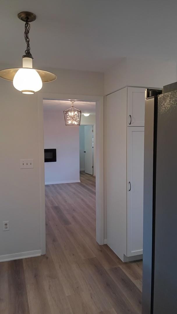 hallway featuring light wood-type flooring and baseboards