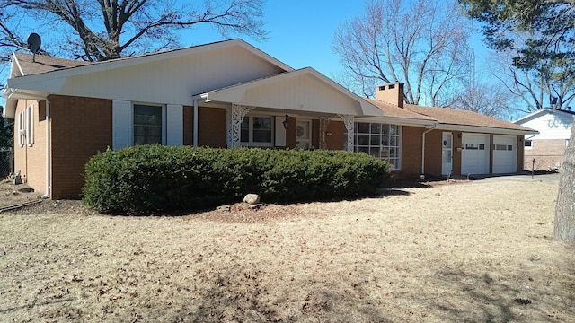 view of front of property with brick siding, driveway, a chimney, and an attached garage