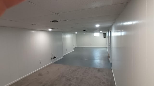 finished below grade area featuring a paneled ceiling, visible vents, and baseboards