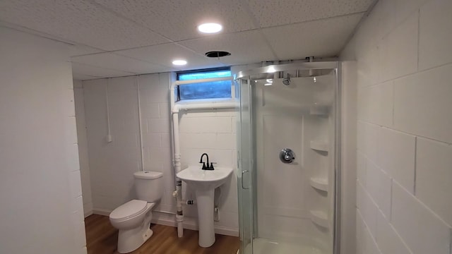 bathroom with toilet, a shower stall, wood finished floors, and concrete block wall