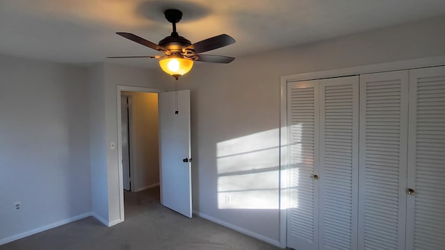 unfurnished bedroom with carpet floors, a closet, baseboards, and a ceiling fan