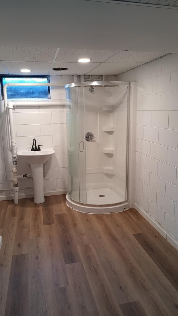 full bath with a drop ceiling, a sink, a shower stall, and wood finished floors