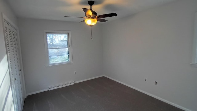 unfurnished bedroom featuring dark colored carpet, a closet, a baseboard heating unit, a ceiling fan, and baseboards