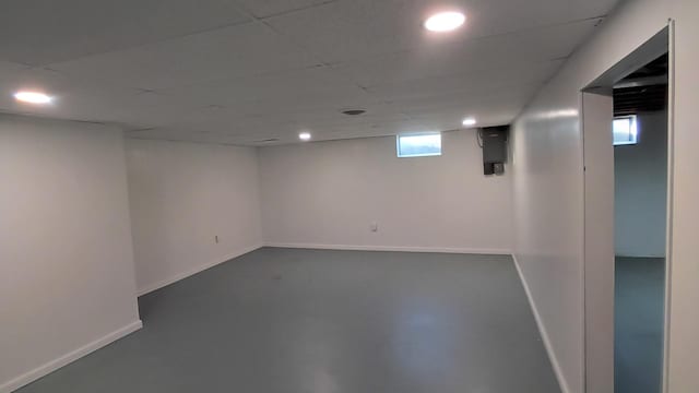 basement with recessed lighting, a paneled ceiling, and baseboards