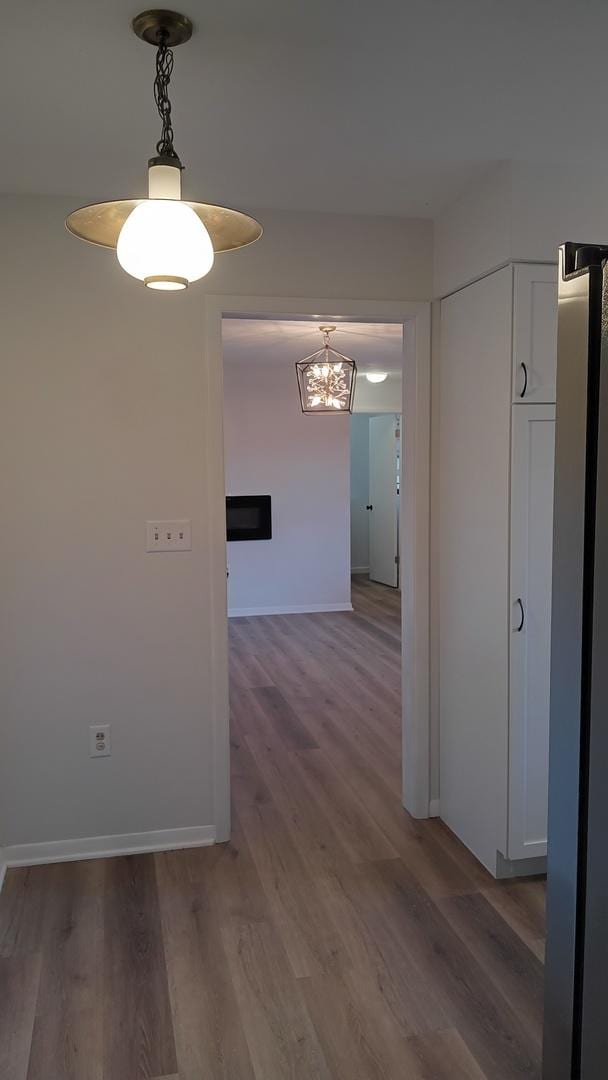 corridor featuring baseboards and light wood finished floors