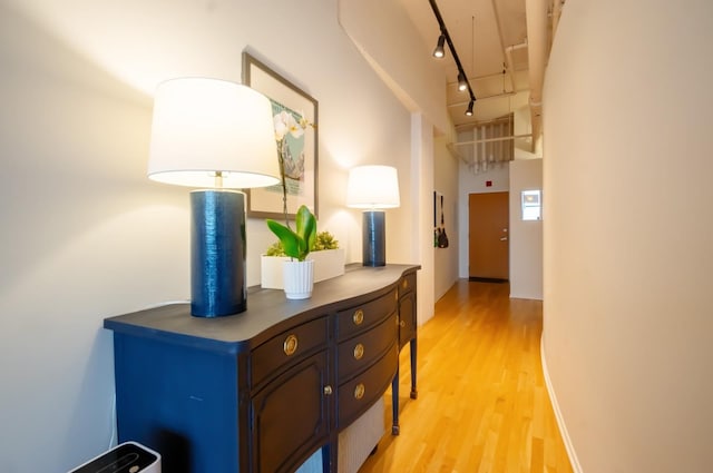 corridor with light wood-style flooring and rail lighting