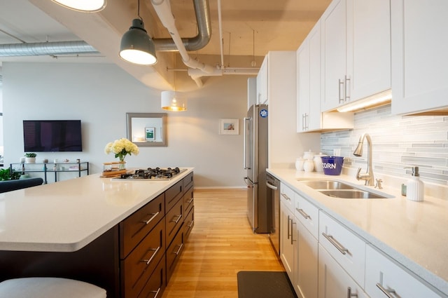 kitchen with light countertops, decorative backsplash, stainless steel appliances, white cabinetry, and a sink