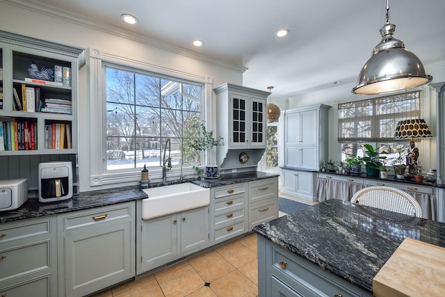 kitchen featuring crown molding, light tile patterned flooring, a sink, and gray cabinetry