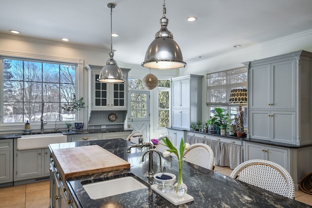 kitchen featuring crown molding, gray cabinets, a sink, and light tile patterned floors