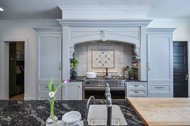 kitchen with high end stove, tasteful backsplash, ornamental molding, and dark stone counters