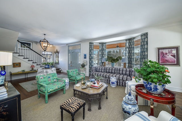 living area with wood finished floors, baseboards, an inviting chandelier, and stairs