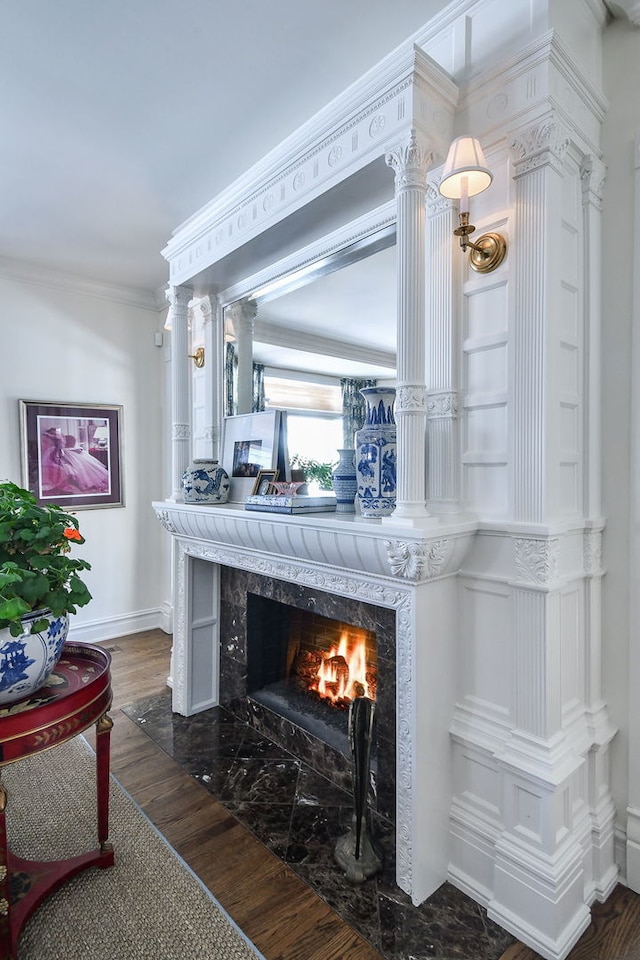 interior details with ornamental molding, a fireplace, baseboards, and wood finished floors