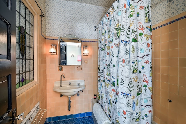 full bath featuring wallpapered walls, tile walls, and a wainscoted wall