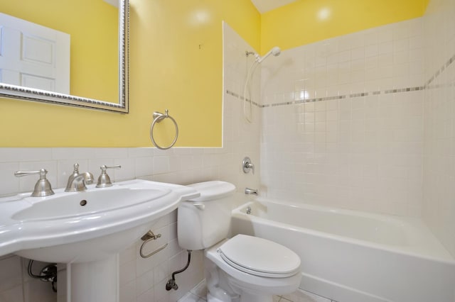 bathroom with wainscoting, tub / shower combination, toilet, and tile walls