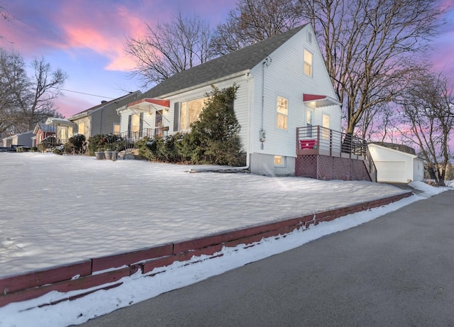 view of snowy exterior featuring an outbuilding and a detached garage