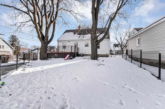 yard covered in snow with fence and a deck