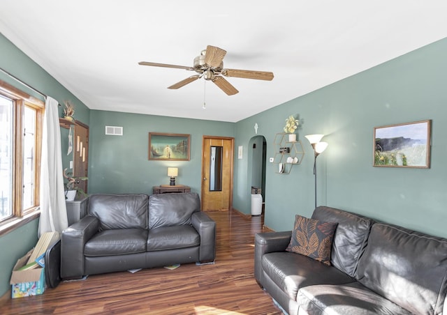 living area with arched walkways, plenty of natural light, wood finished floors, and visible vents