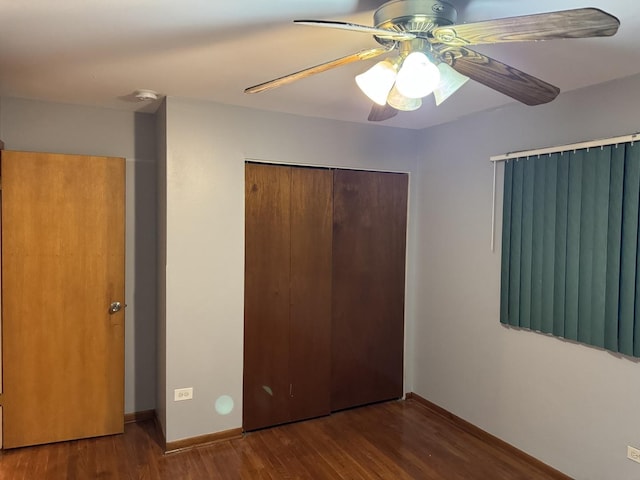 unfurnished bedroom featuring ceiling fan, dark hardwood / wood-style flooring, and a closet