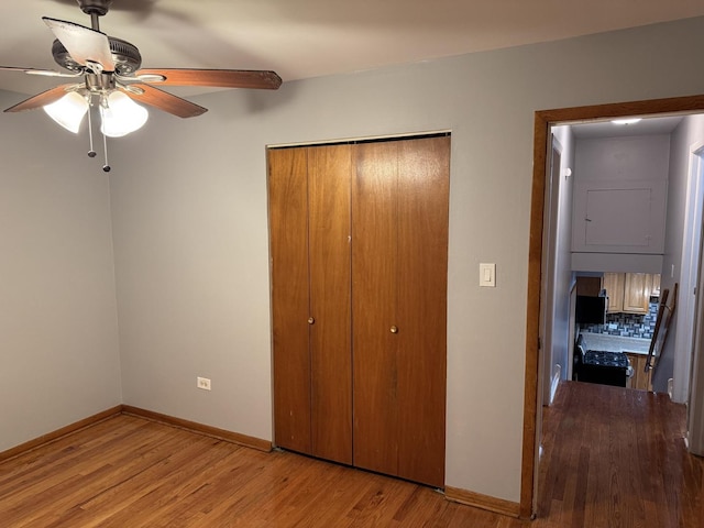 unfurnished bedroom featuring ceiling fan, a closet, and light wood-type flooring