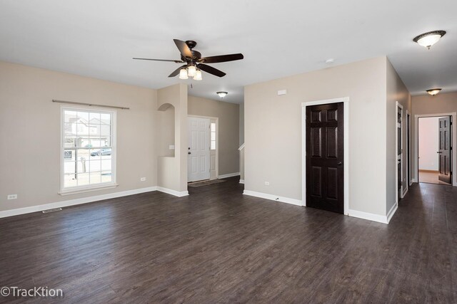 unfurnished living room featuring visible vents, baseboards, dark wood-type flooring, and a ceiling fan