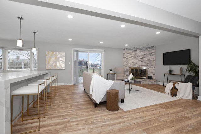 living room featuring a stone fireplace and light hardwood / wood-style floors