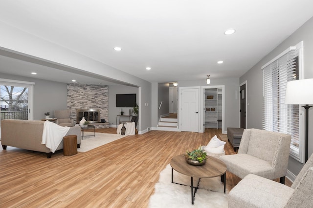 living room with a stone fireplace and light hardwood / wood-style flooring