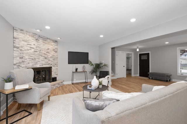 living room with a stone fireplace and light wood-type flooring