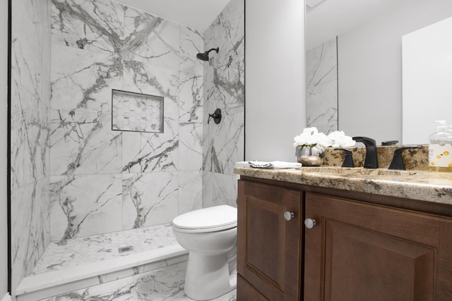 bathroom with vanity, tiled shower, and toilet