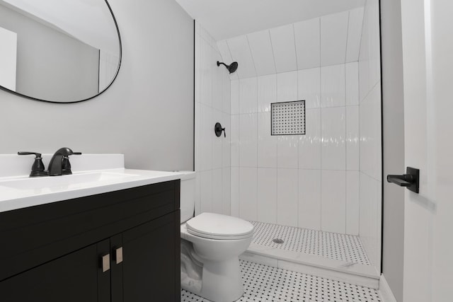 bathroom with vanity, tiled shower, and toilet