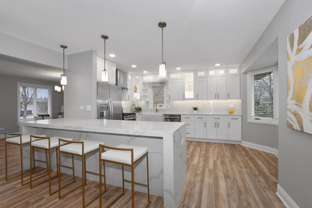 kitchen featuring appliances with stainless steel finishes, decorative light fixtures, light stone countertops, and white cabinets