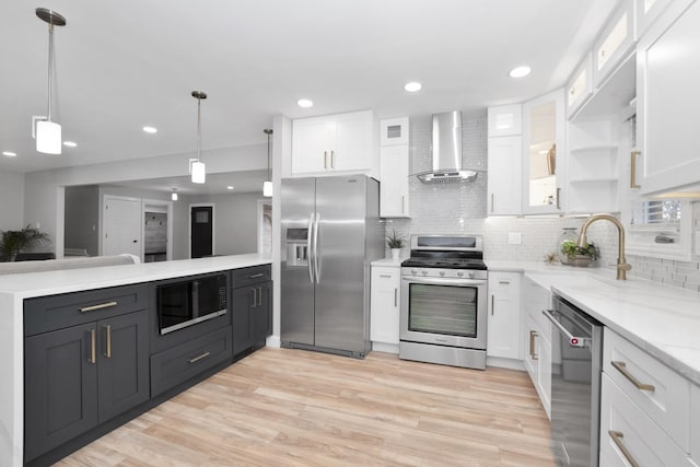 kitchen with white cabinetry, sink, stainless steel appliances, and wall chimney exhaust hood