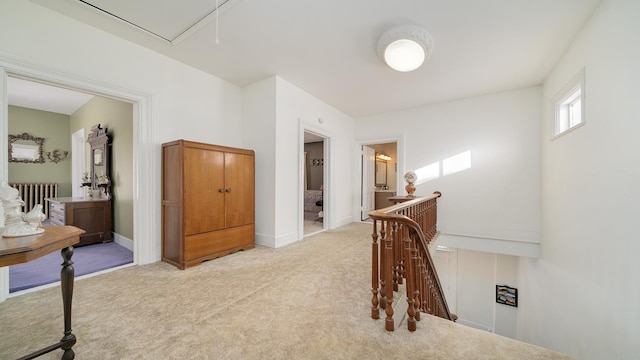 corridor featuring light colored carpet and radiator heating unit