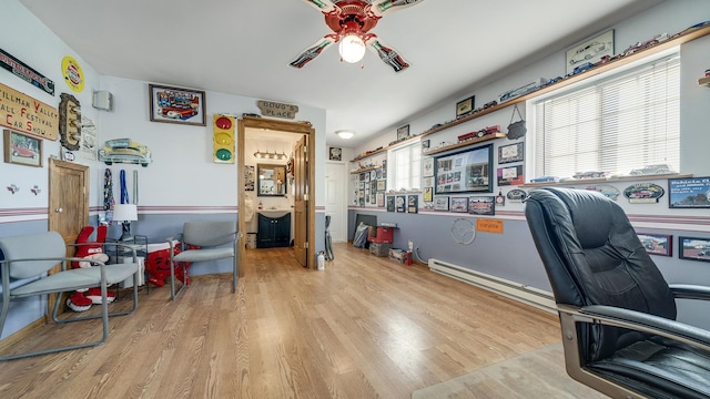 office space featuring a baseboard heating unit, ceiling fan, and light hardwood / wood-style flooring