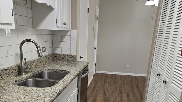 kitchen featuring dishwasher, sink, light stone countertops, and white cabinets