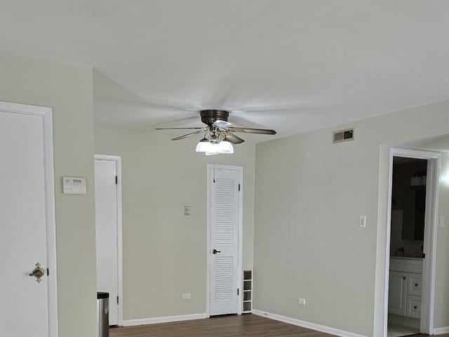 unfurnished bedroom with dark wood-type flooring, connected bathroom, and ceiling fan