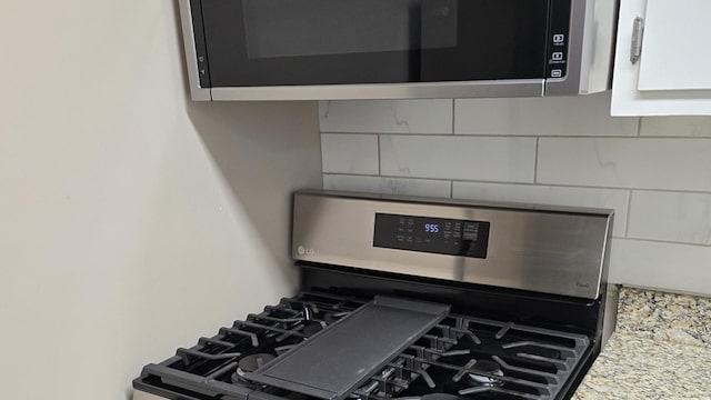 details with white cabinets, stainless steel appliances, and light stone counters