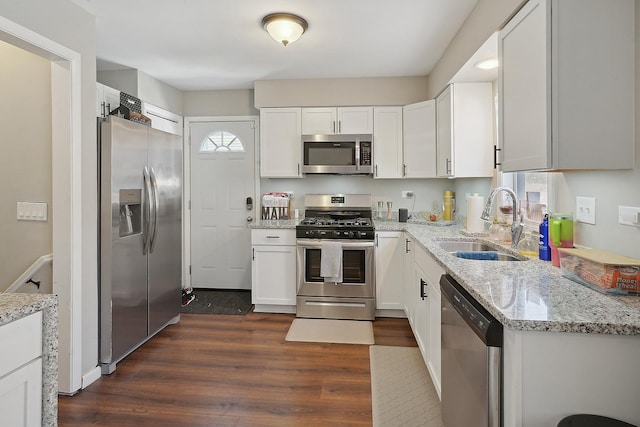 kitchen with white cabinetry, stainless steel appliances, light stone countertops, and sink