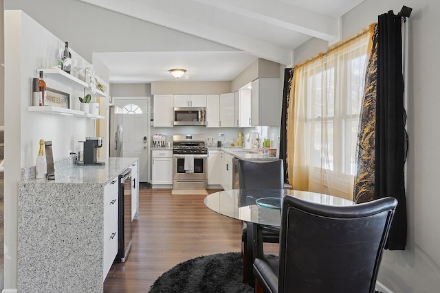 kitchen with a wealth of natural light, white cabinetry, sink, stainless steel appliances, and light stone countertops