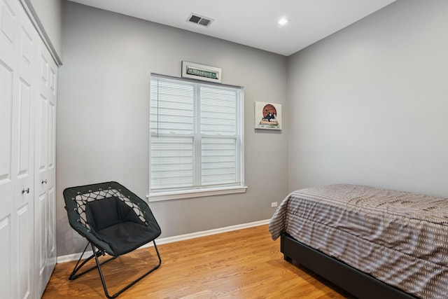 bedroom featuring a closet, baseboards, visible vents, and wood finished floors