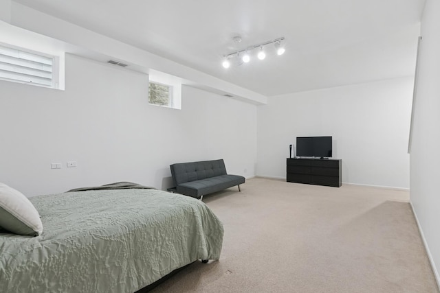 carpeted bedroom with visible vents, baseboards, and rail lighting