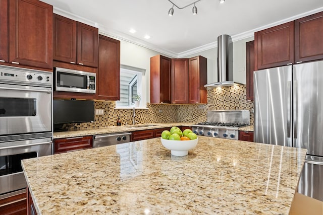 kitchen with ornamental molding, a sink, a kitchen island, appliances with stainless steel finishes, and wall chimney range hood