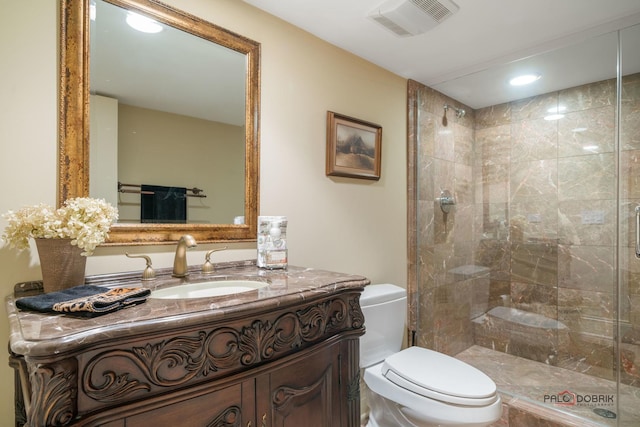 bathroom featuring a shower with door, vanity, and toilet