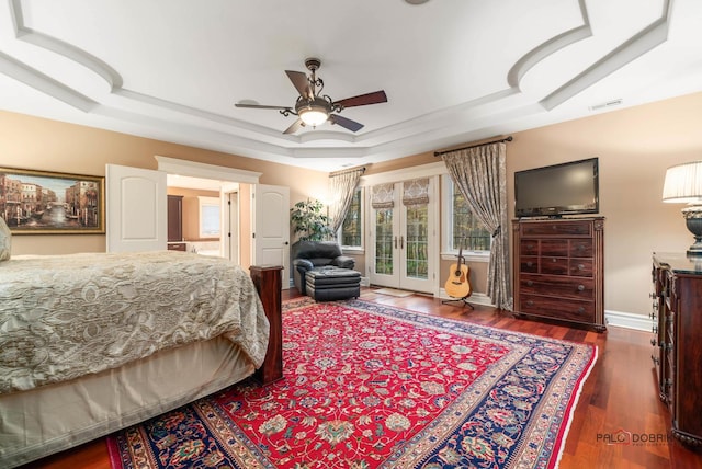 bedroom with dark hardwood / wood-style floors, access to outside, ceiling fan, a raised ceiling, and french doors