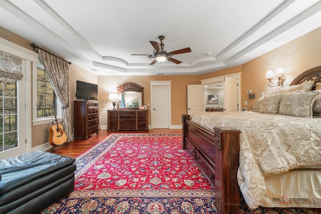 bedroom featuring access to exterior, wood-type flooring, a raised ceiling, and ceiling fan