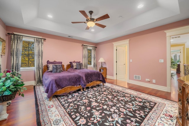 bedroom with a raised ceiling, hardwood / wood-style flooring, and ceiling fan