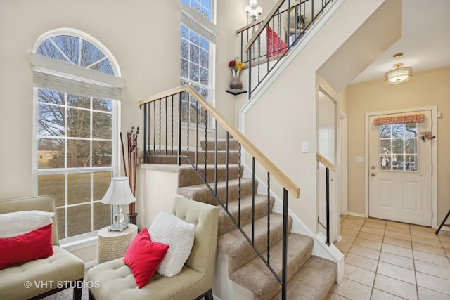 foyer entrance featuring light tile patterned floors and a towering ceiling