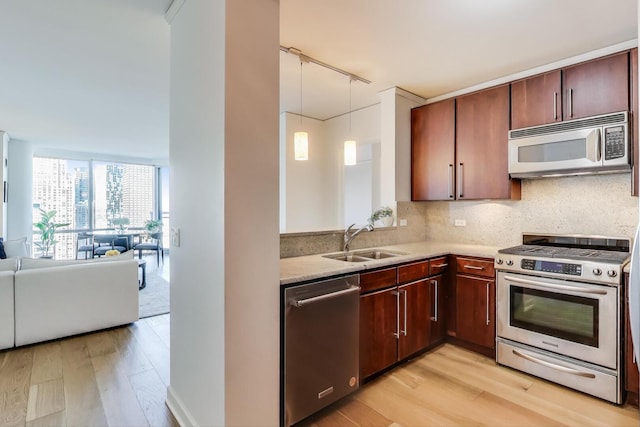 kitchen featuring a sink, light wood-style floors, backsplash, and appliances with stainless steel finishes